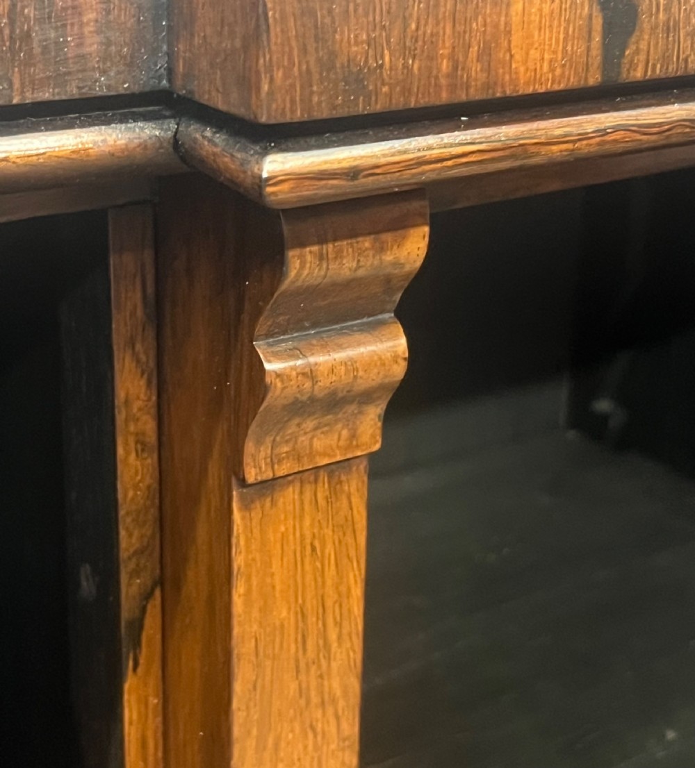 A low, wide Late Regency open rosewood bookcase featuring a breakfront top, three divided shelving sections, and a solid plinth base. View X