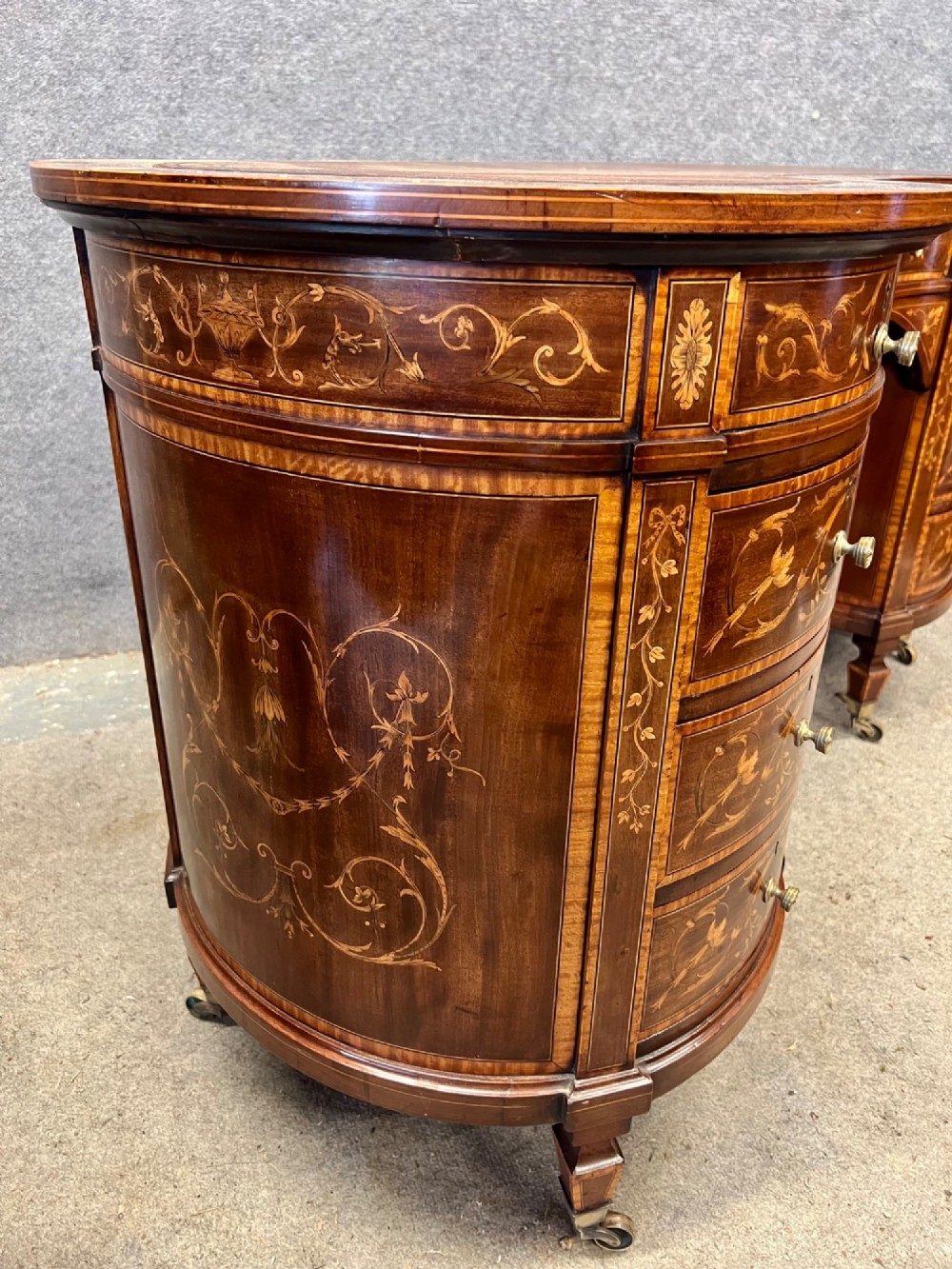 An Edwardian mahogany kidney-shaped desk featuring detailed floral marquetry inlay, a tooled leather writing surface, multiple drawers, and brass castors. View VI
