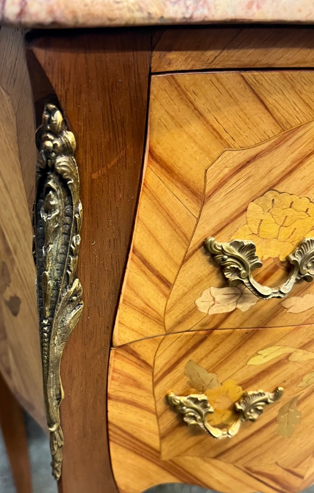 A pair of French Louis XV style bedside chests featuring floral marquetry inlay, curved cabriole legs, decorative metal mounts, and shaped pink marble tops. View X
