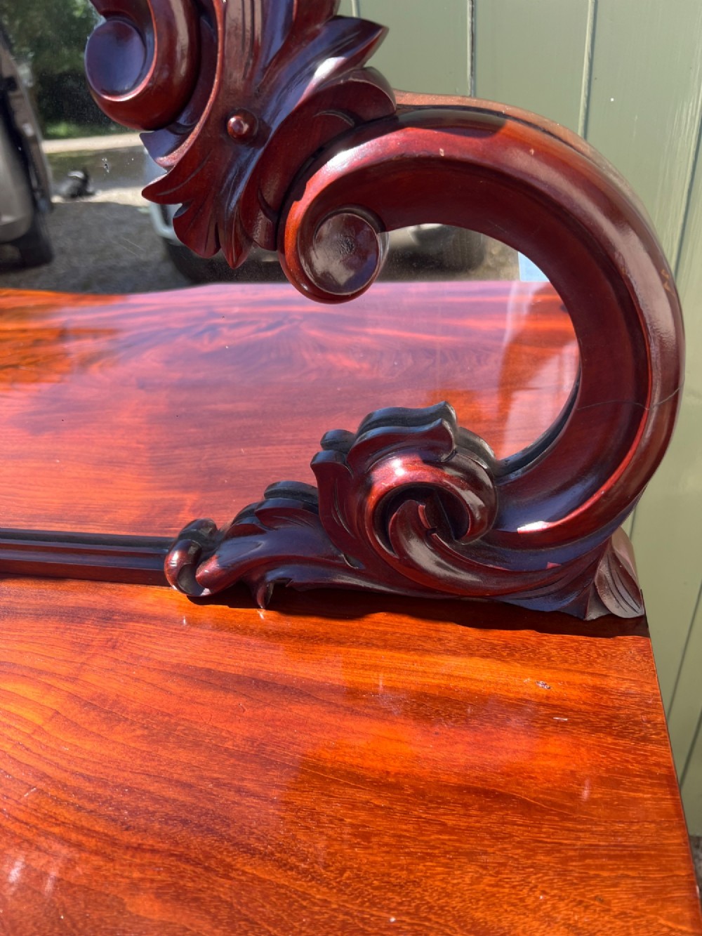 A nineteenth-century mahogany sideboard featuring a large carved mirror frame upstand, central double cupboard doors, flanking side doors with scroll mouldings, and flame timber veneers. View VIII