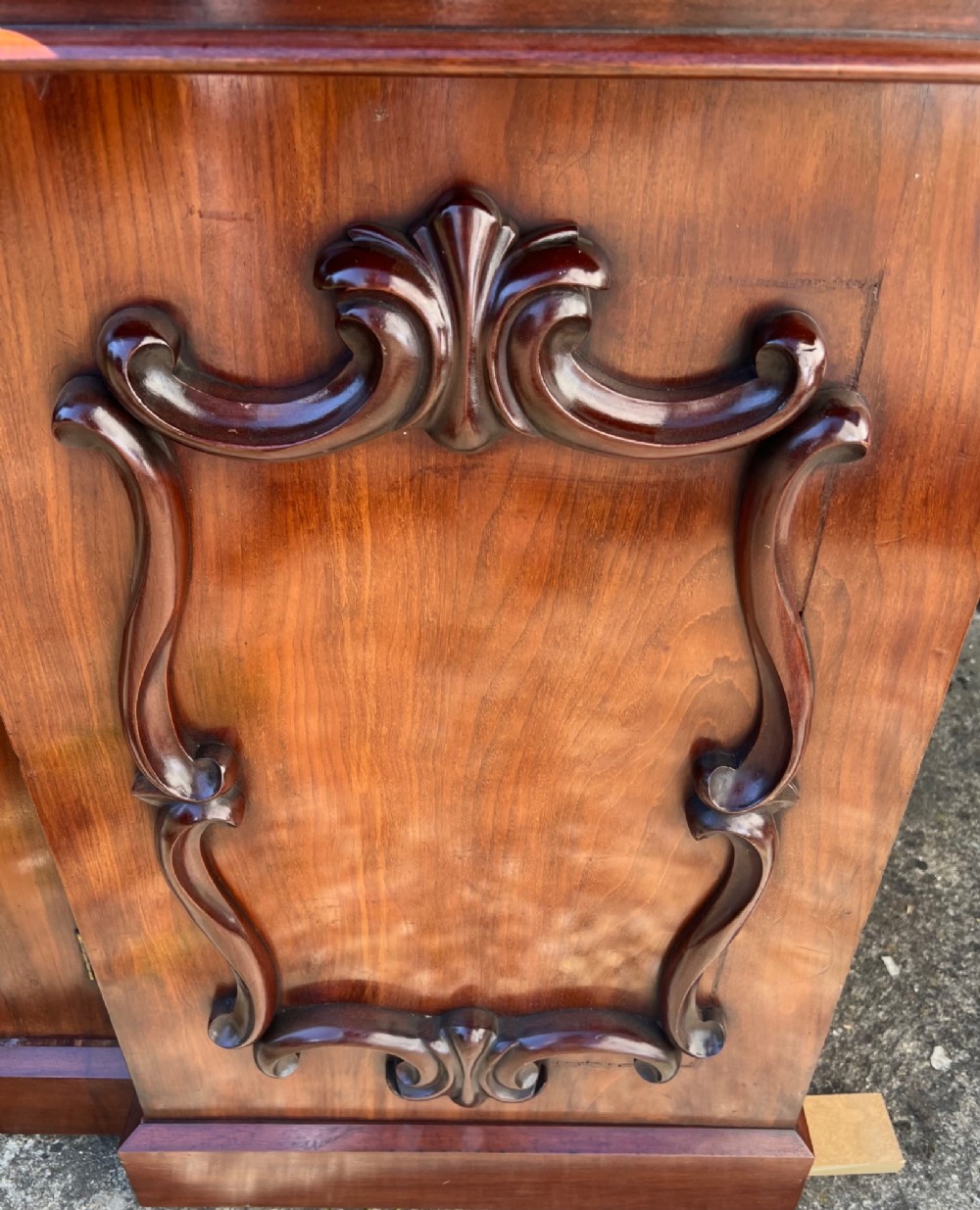 A nineteenth-century mahogany sideboard featuring a large carved mirror frame upstand, central double cupboard doors, flanking side doors with scroll mouldings, and flame timber veneers. View X