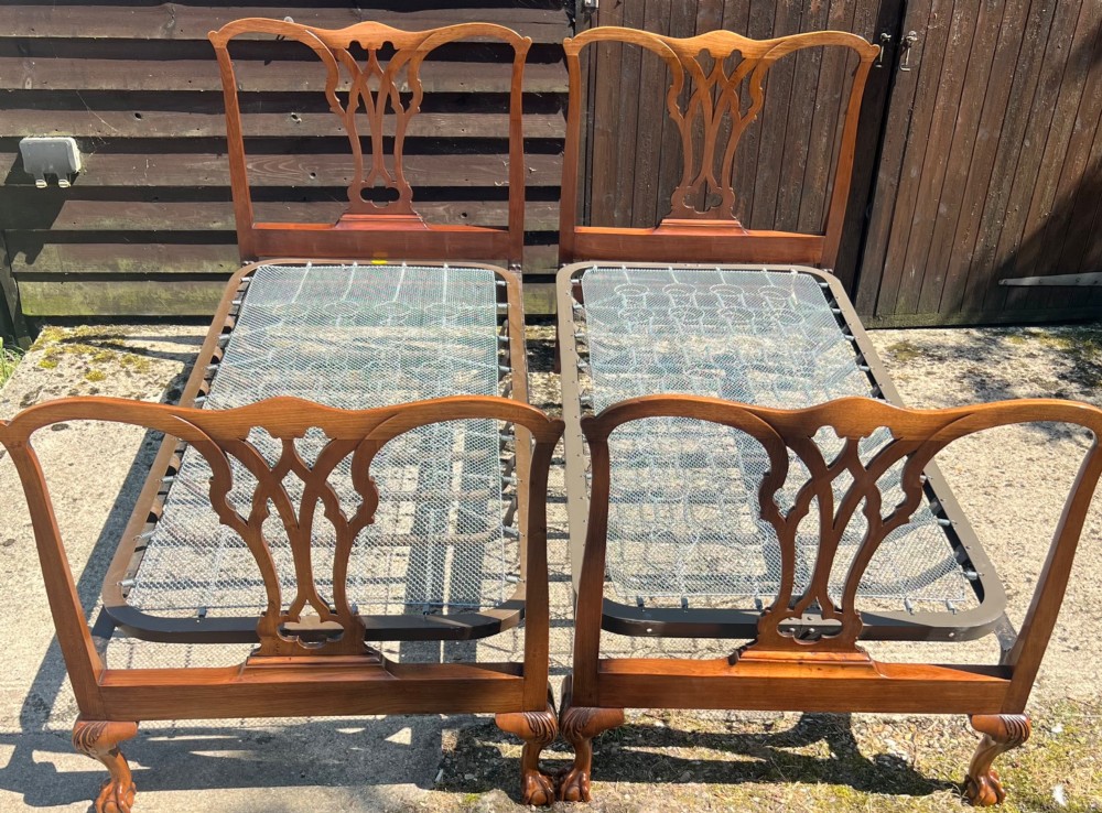 A pair of antique Chippendale style mahogany single bed frames featuring carved pierced back splats, yoke crest rails, and cabriole legs ending in claw and ball feet.