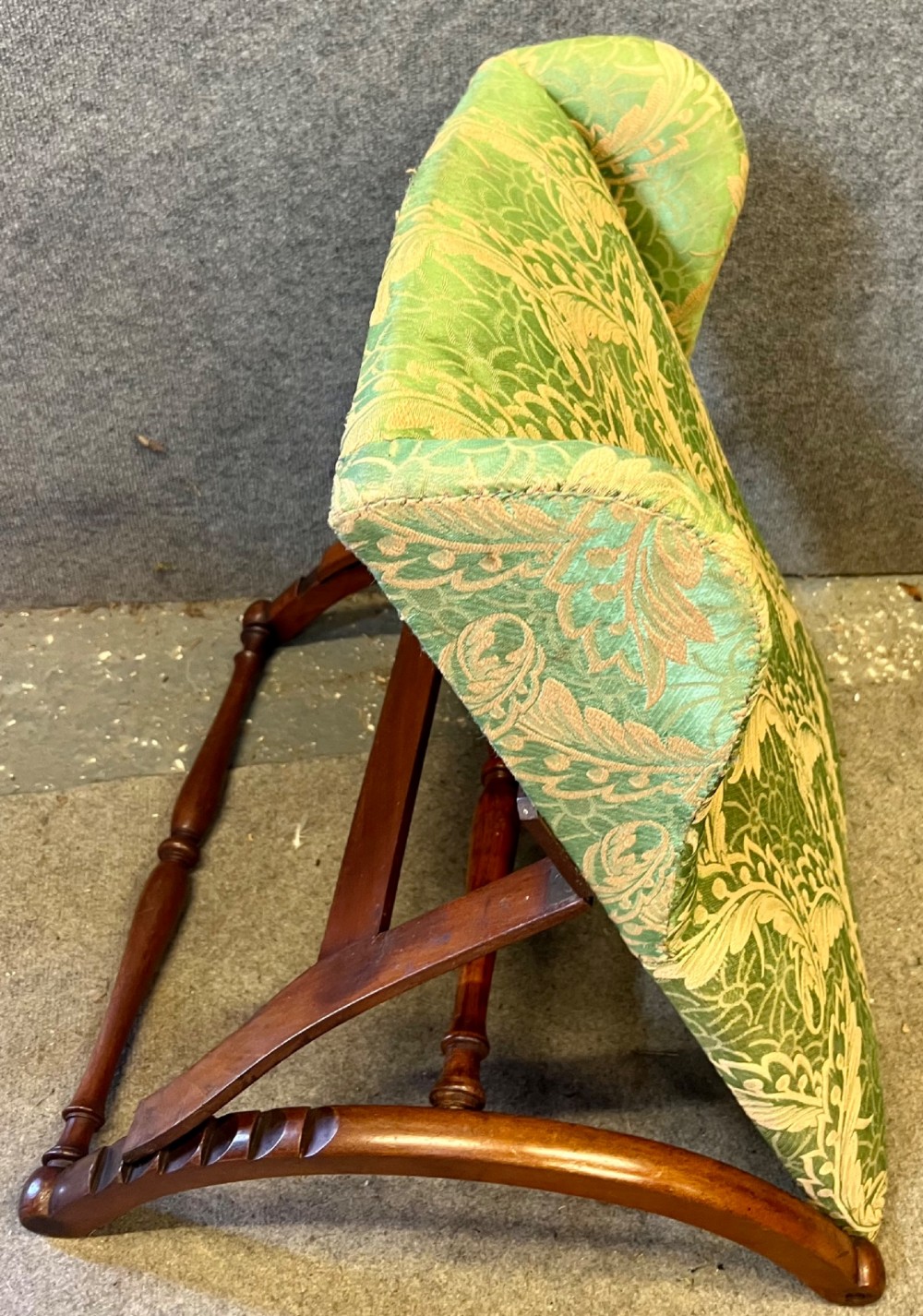 A Victorian campaign adjustable wooden backrest frame upholstered in patterned green fabric with notched timber ratchets for support.