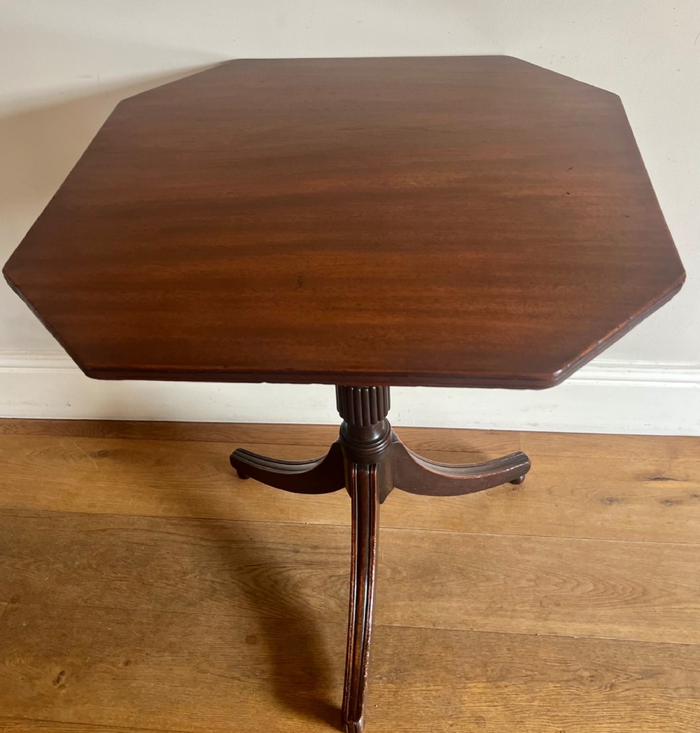 A George III mahogany tilt-top table featuring an octagonal top set on a reeded turned column and a splayed tripod base. View II