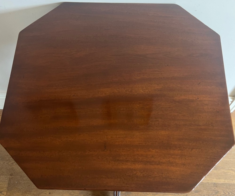 A George III mahogany tilt-top table featuring an octagonal top set on a reeded turned column and a splayed tripod base. View IV