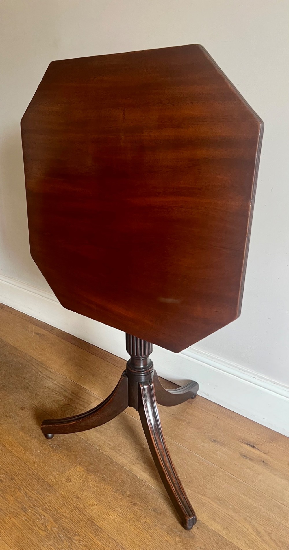 A George III mahogany tilt-top table featuring an octagonal top set on a reeded turned column and a splayed tripod base. View VII