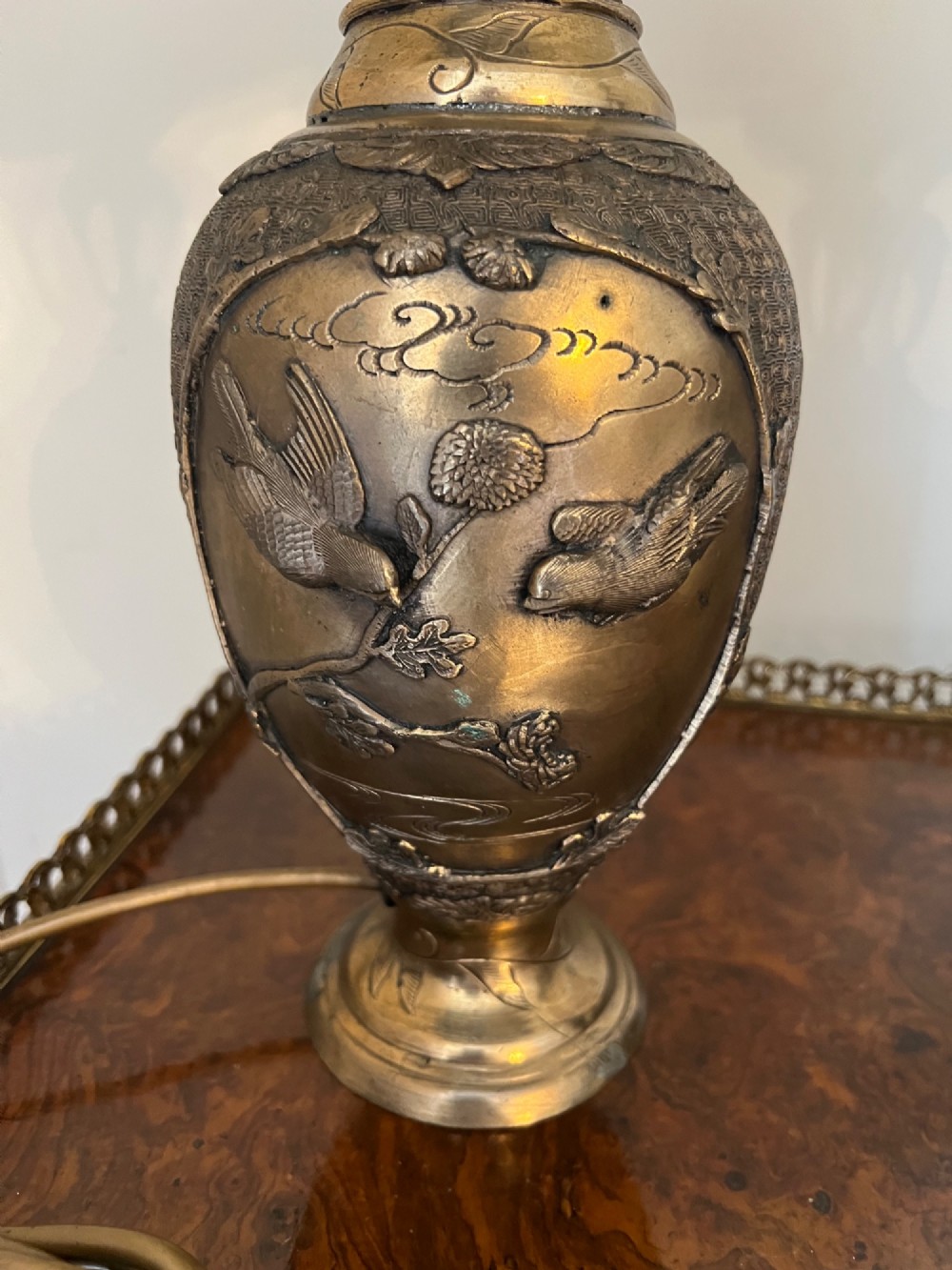 A pair of Japanese Meiji period bronze vase table lamps featuring relief bird and botanical motifs with pleated cream fabric lampshades. View VI