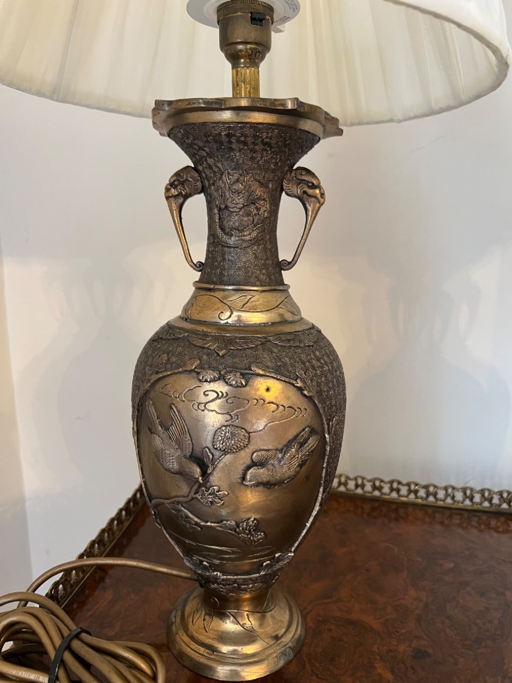 A pair of Japanese Meiji period bronze vase table lamps featuring relief bird and botanical motifs with pleated cream fabric lampshades. View IX