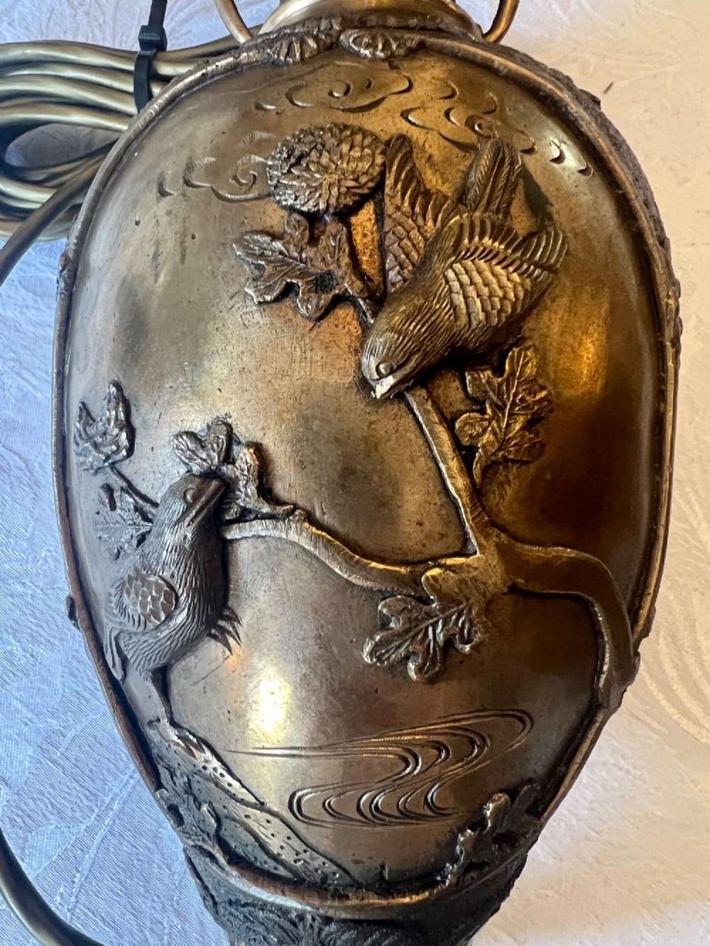 A pair of Japanese Meiji period bronze vase table lamps featuring relief bird and botanical motifs with pleated cream fabric lampshades. View XI