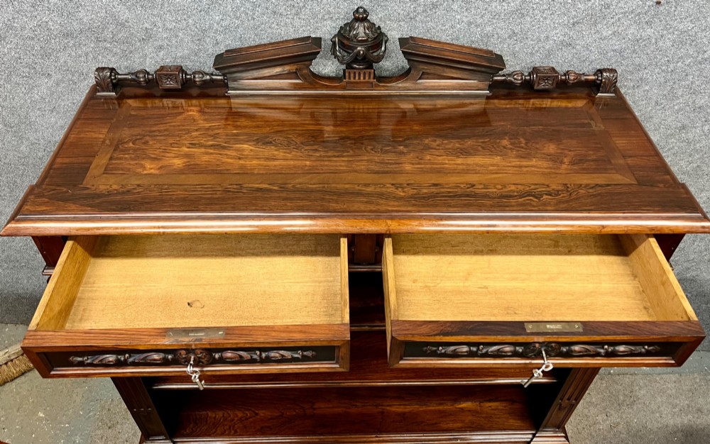 A Victorian dark walnut open bookcase with two carved drawers, open shelves, fluted pilasters, and a decorative pediment top featuring a central urn finial. View III
