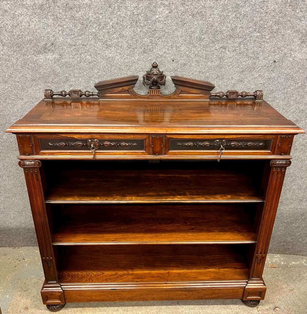 A Victorian dark walnut open bookcase with two carved drawers, open shelves, fluted pilasters, and a decorative pediment top featuring a central urn finial. View XI