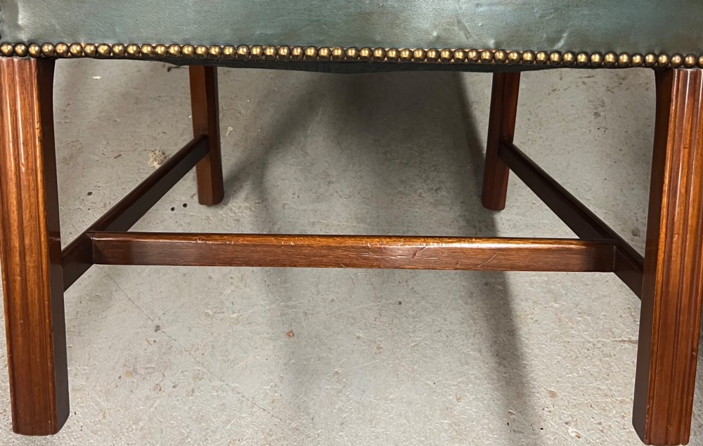 A Gainsborough style desk chair upholstered in patinated green leather with brass stud trimming and carved mahogany arm supports. View III
