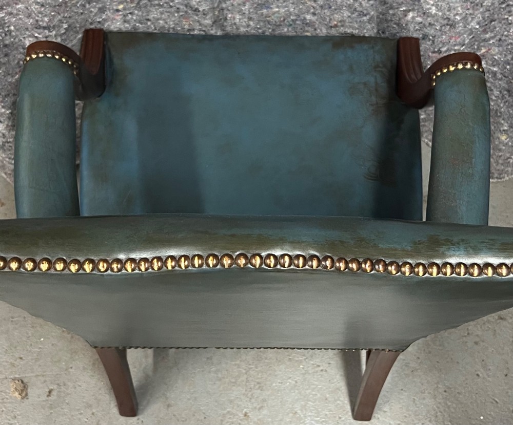 A Gainsborough style desk chair upholstered in patinated green leather with brass stud trimming and carved mahogany arm supports. View IV