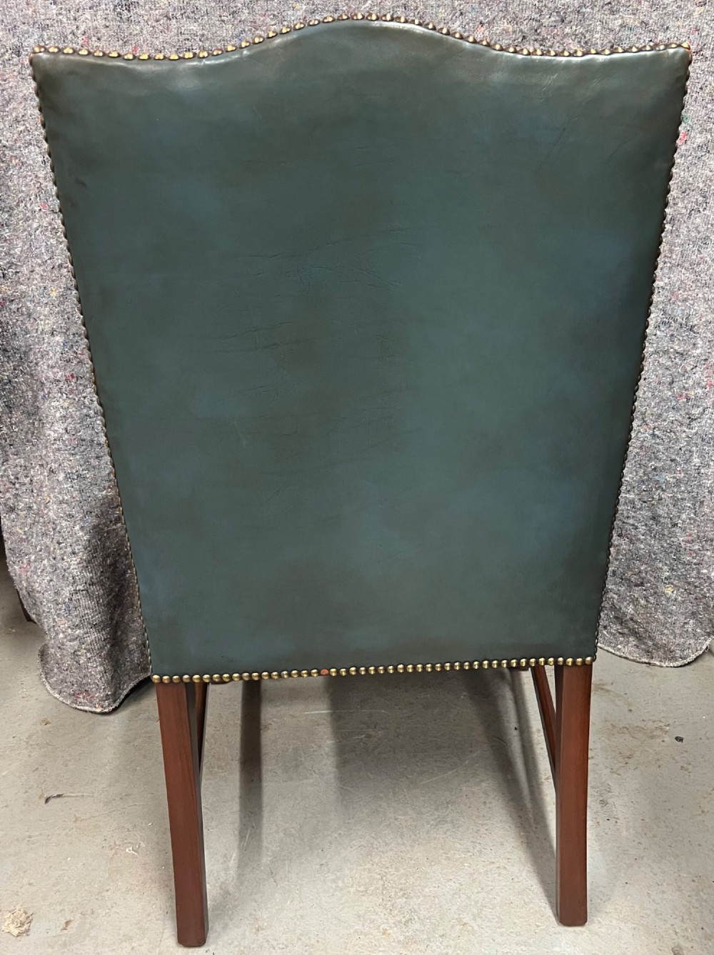A Gainsborough style desk chair upholstered in patinated green leather with brass stud trimming and carved mahogany arm supports. View V