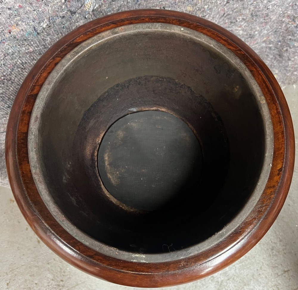 An Edwardian mahogany jardiniere plant stand featuring a slatted circular bucket with internal metal lining, supported by three curved legs and a triangular base stretcher. View VI