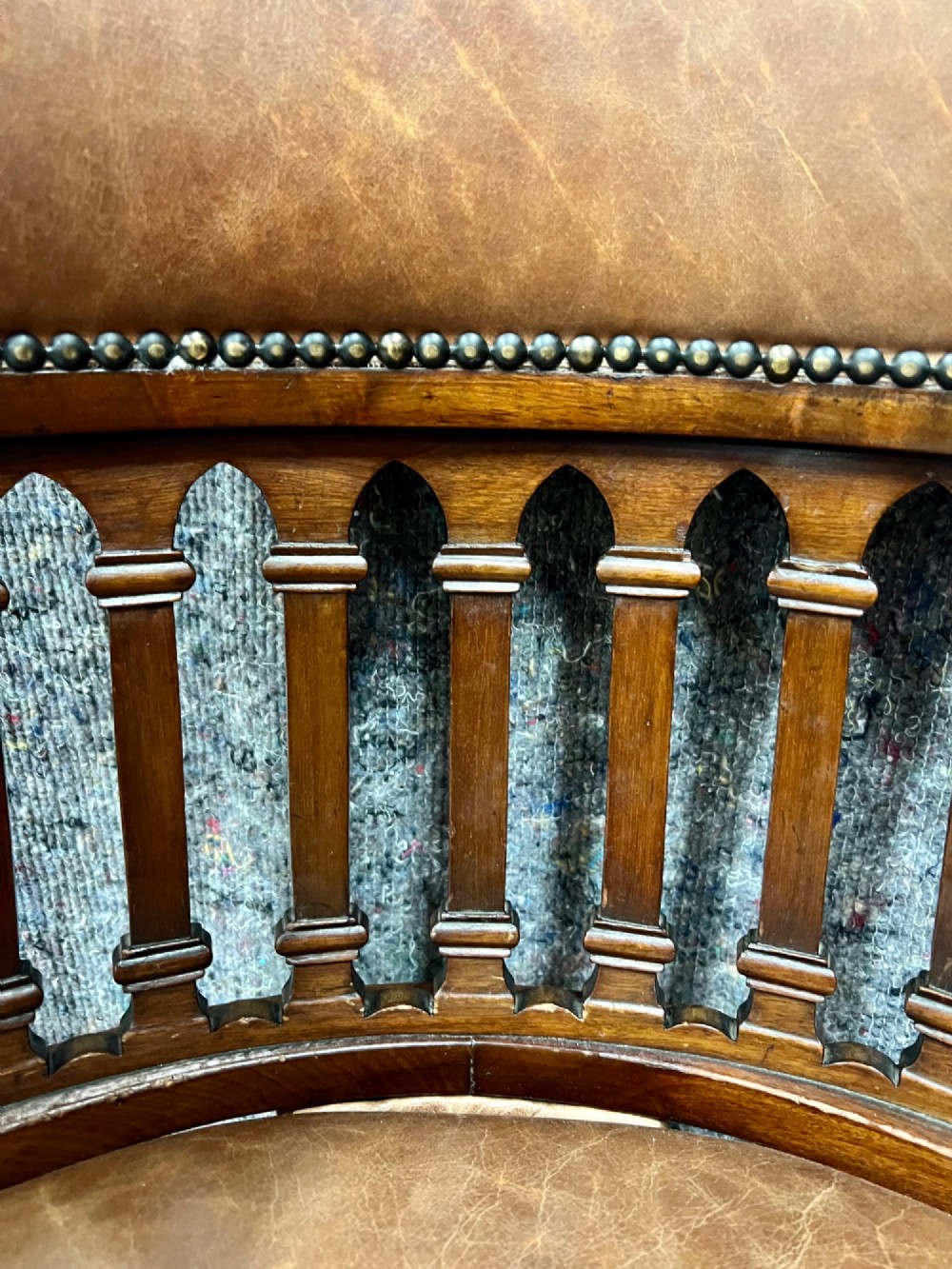 A Victorian mahogany revolving desk chair with tan leather padded seating, brass stud detailing, and a turned spindle gallery backrest. View III