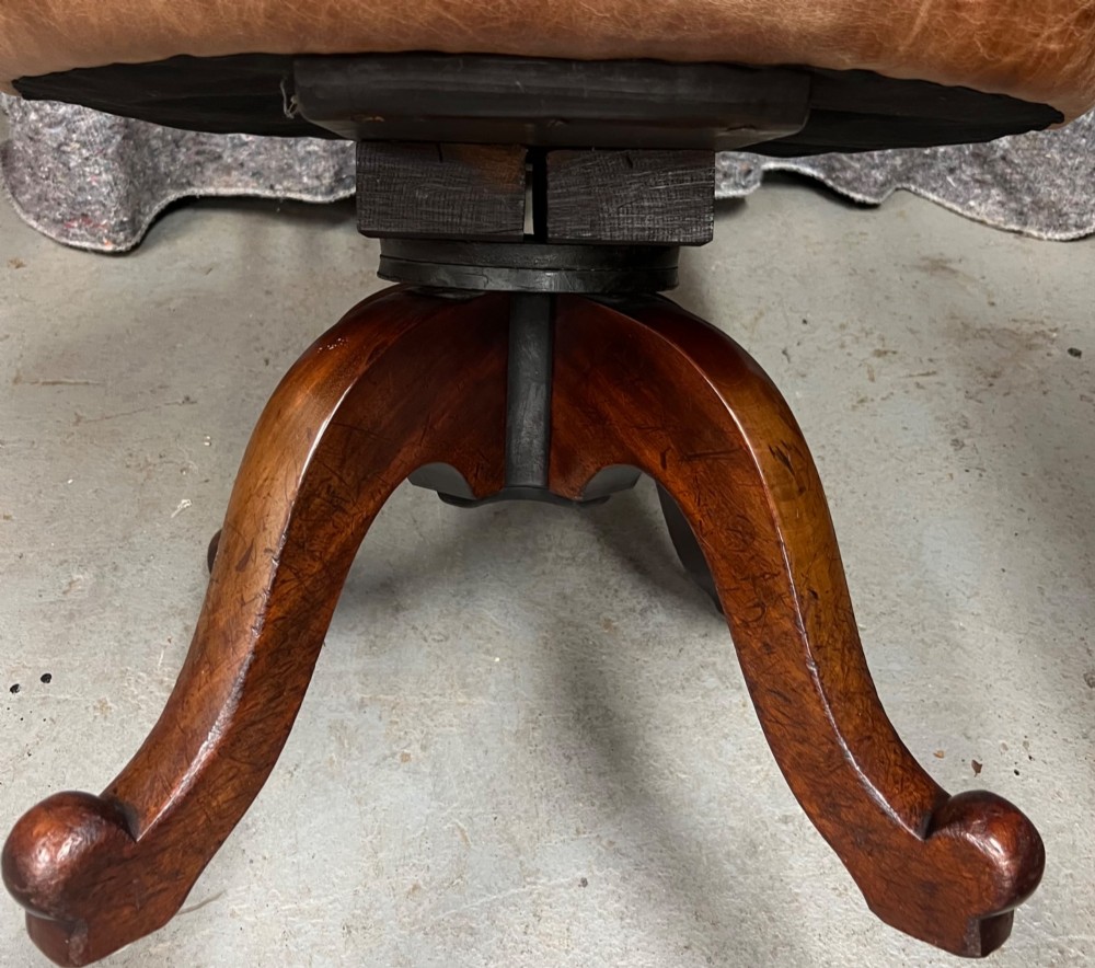 A Victorian mahogany revolving desk chair with tan leather padded seating, brass stud detailing, and a turned spindle gallery backrest. View VI
