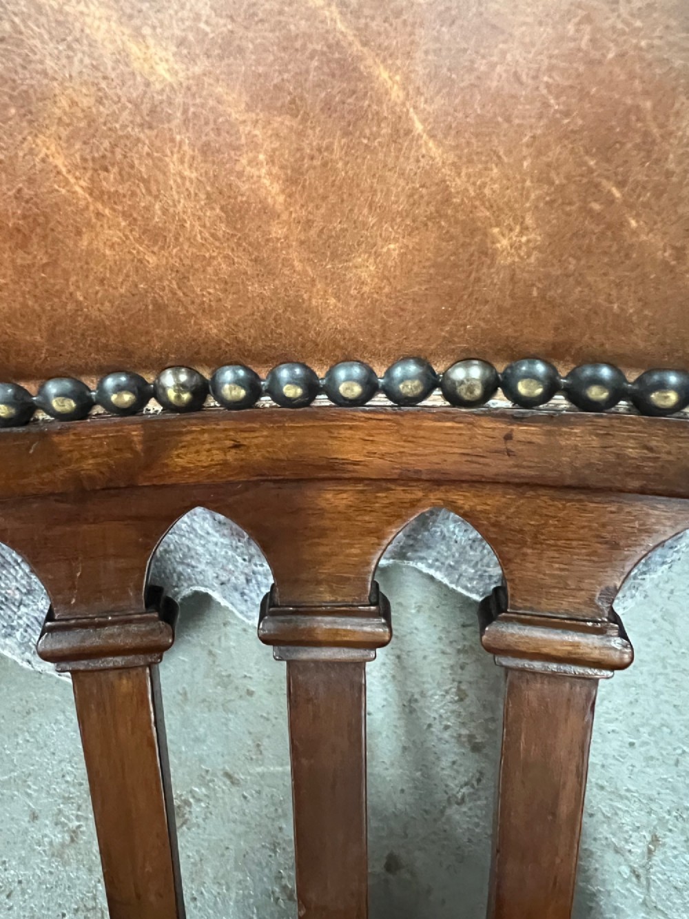 A Victorian mahogany revolving desk chair with tan leather padded seating, brass stud detailing, and a turned spindle gallery backrest. View VIII