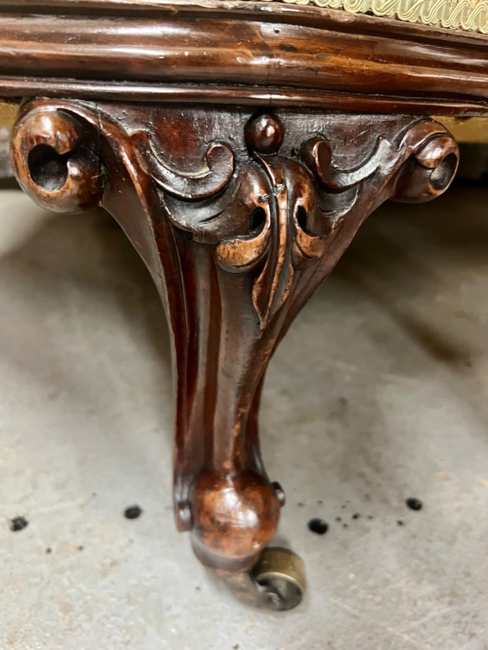 A Victorian small settee with a carved mahogany frame, pale green floral damask fabric, pierced arm supports, and cabriole legs on brass castors. View III
