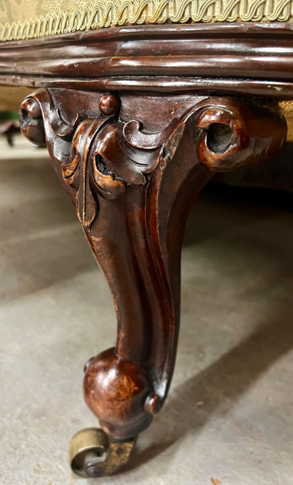 A Victorian small settee with a carved mahogany frame, pale green floral damask fabric, pierced arm supports, and cabriole legs on brass castors. View IV