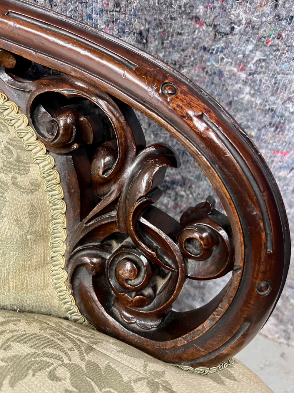 A Victorian small settee with a carved mahogany frame, pale green floral damask fabric, pierced arm supports, and cabriole legs on brass castors. View VI