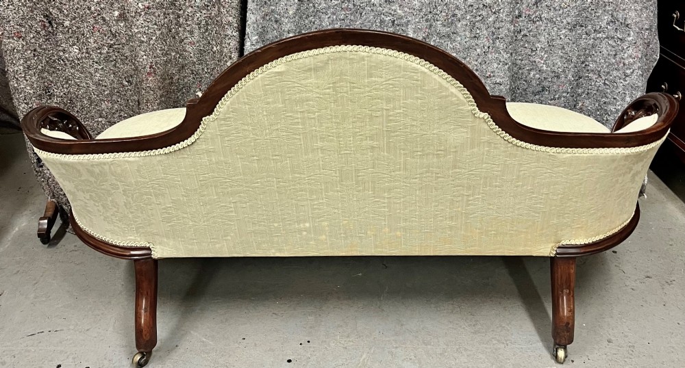 A Victorian small settee with a carved mahogany frame, pale green floral damask fabric, pierced arm supports, and cabriole legs on brass castors. View VIII