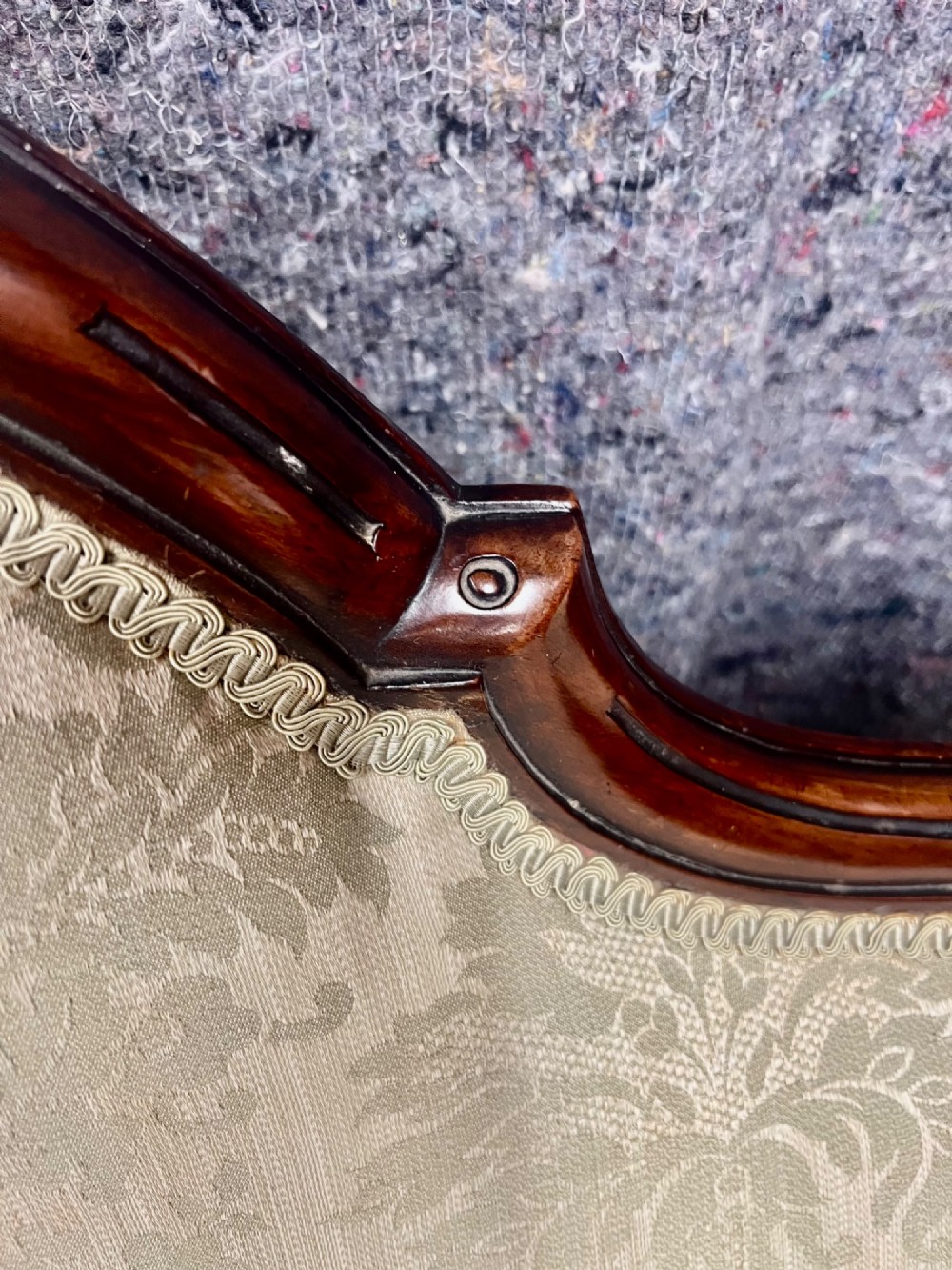 A Victorian small settee with a carved mahogany frame, pale green floral damask fabric, pierced arm supports, and cabriole legs on brass castors. View X