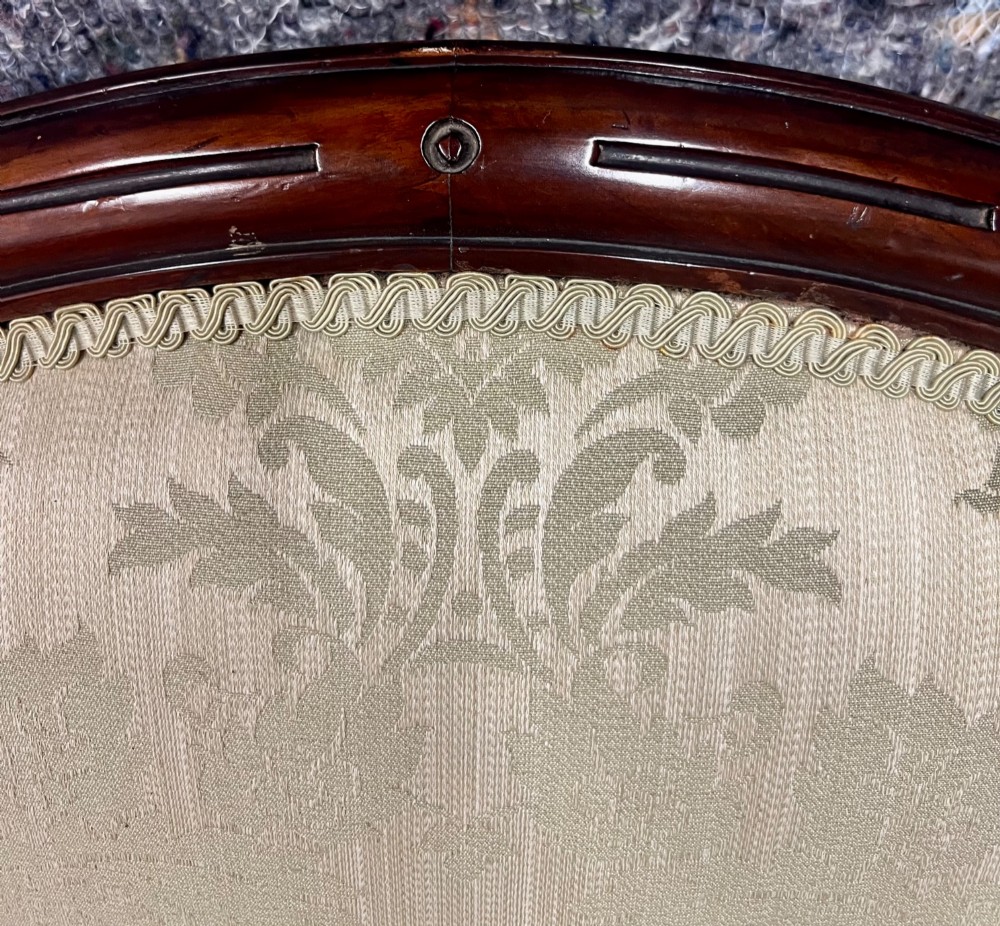 A Victorian small settee with a carved mahogany frame, pale green floral damask fabric, pierced arm supports, and cabriole legs on brass castors. View XI