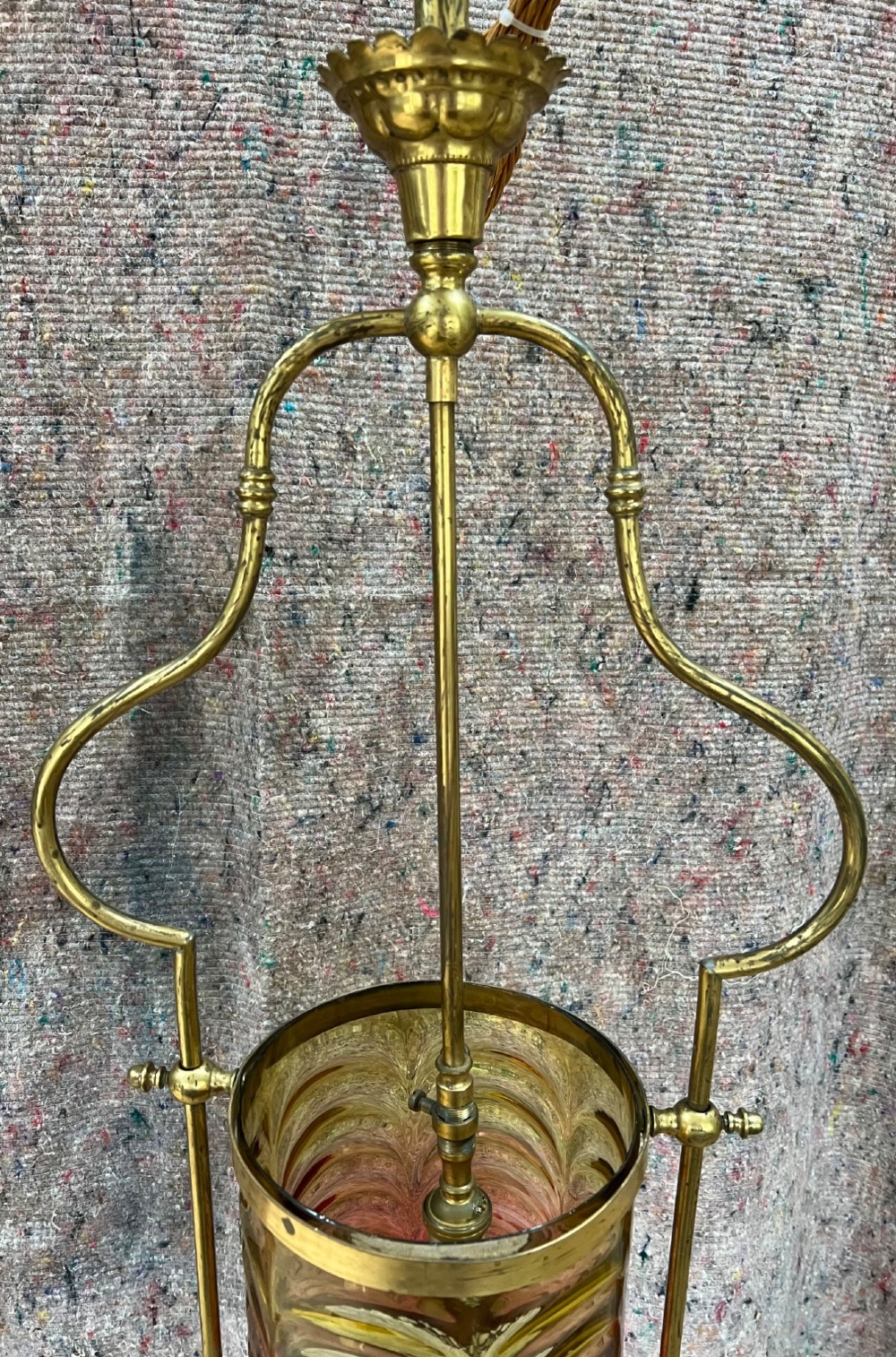 An antique brass hanging pendant lantern featuring a contoured brass frame suspending a moulded pink and amber glass shade. View V