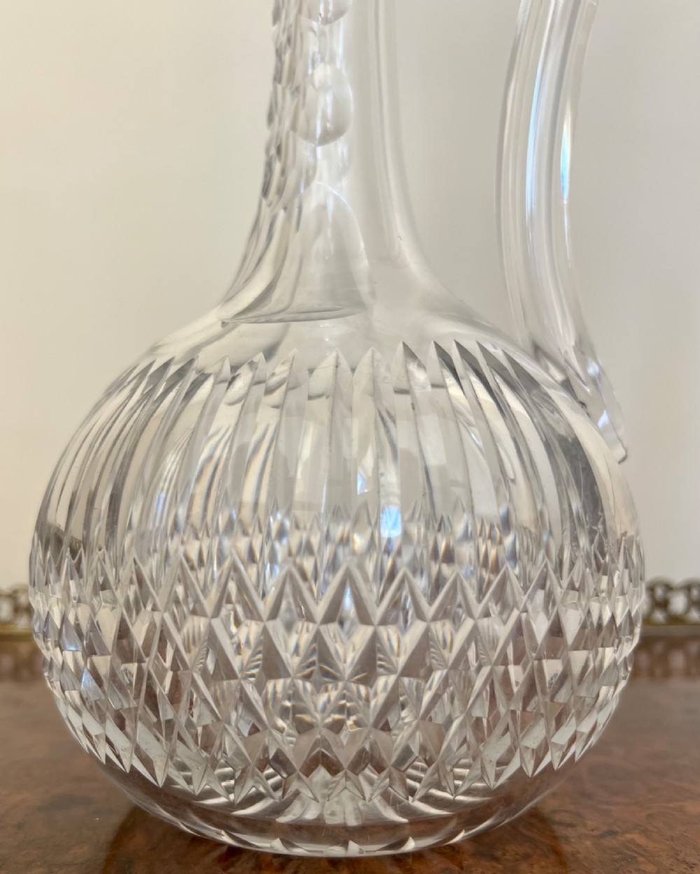 An Edwardian clear cut glass claret jug featuring a diamond-cut pattern body, an elongated handle, and a faceted spherical stopper. View II