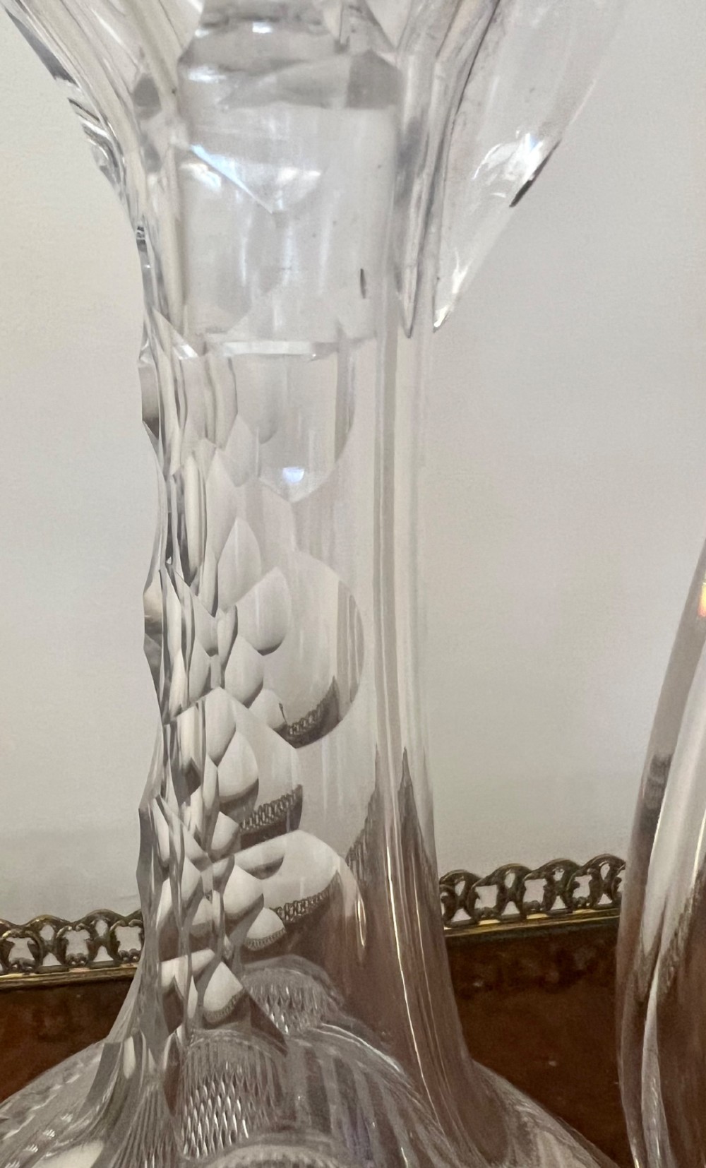 An Edwardian clear cut glass claret jug featuring a diamond-cut pattern body, an elongated handle, and a faceted spherical stopper. View VI