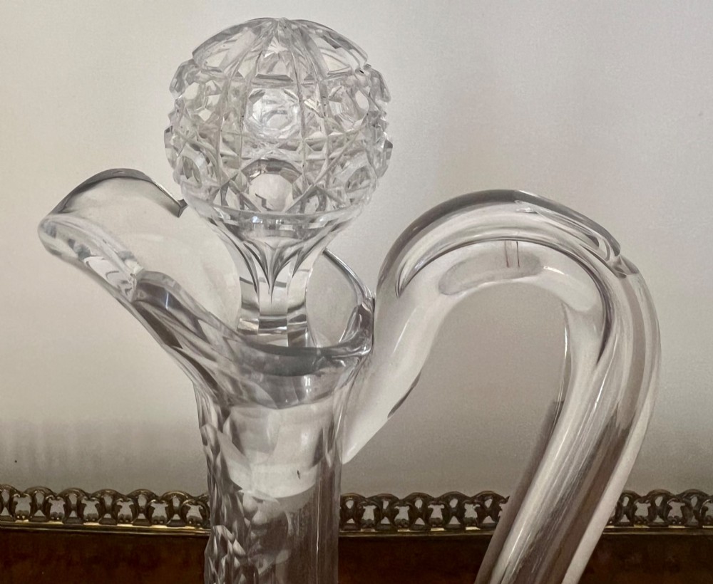 An Edwardian clear cut glass claret jug featuring a diamond-cut pattern body, an elongated handle, and a faceted spherical stopper. View VIII