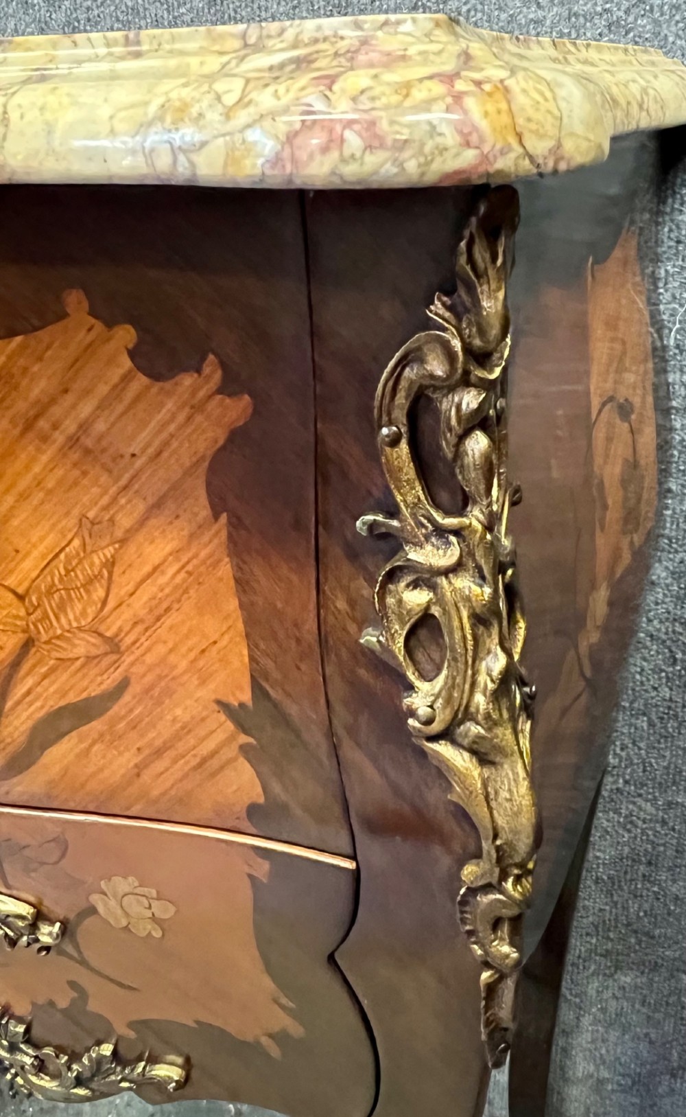 A pair of French Louis XV style bedside tables featuring marble tops, two floral marquetry drawers, gilt-bronze mounts, and slender cabriole legs. View V