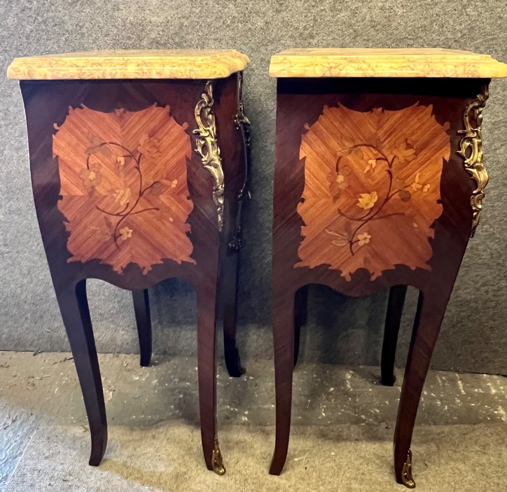 A pair of French Louis XV style bedside tables featuring marble tops, two floral marquetry drawers, gilt-bronze mounts, and slender cabriole legs. View X
