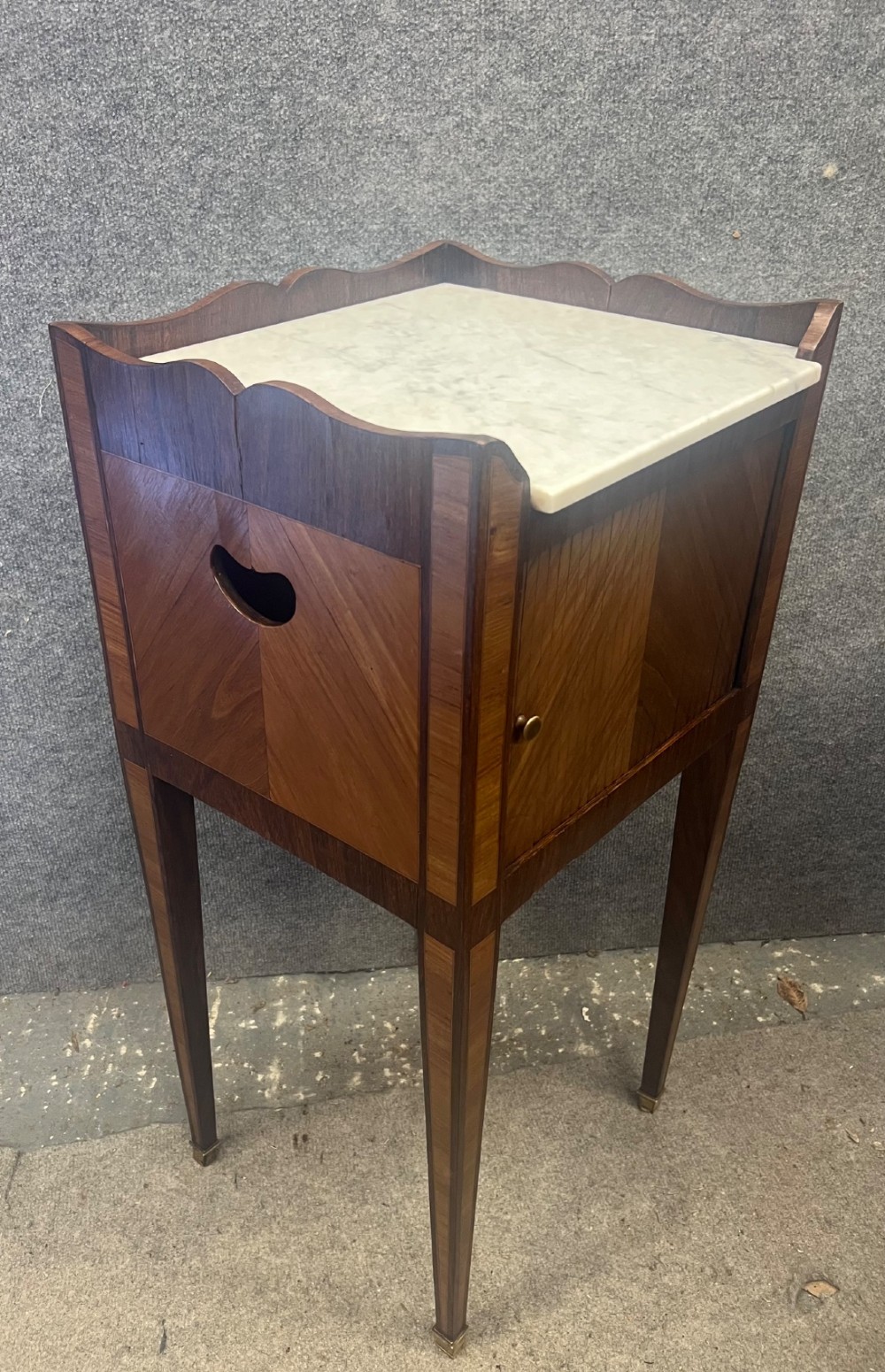 A pair of slender French bedside cabinets featuring chevron wood parquetry doors, white marble tops, and long tapered legs with brass feet. View VI