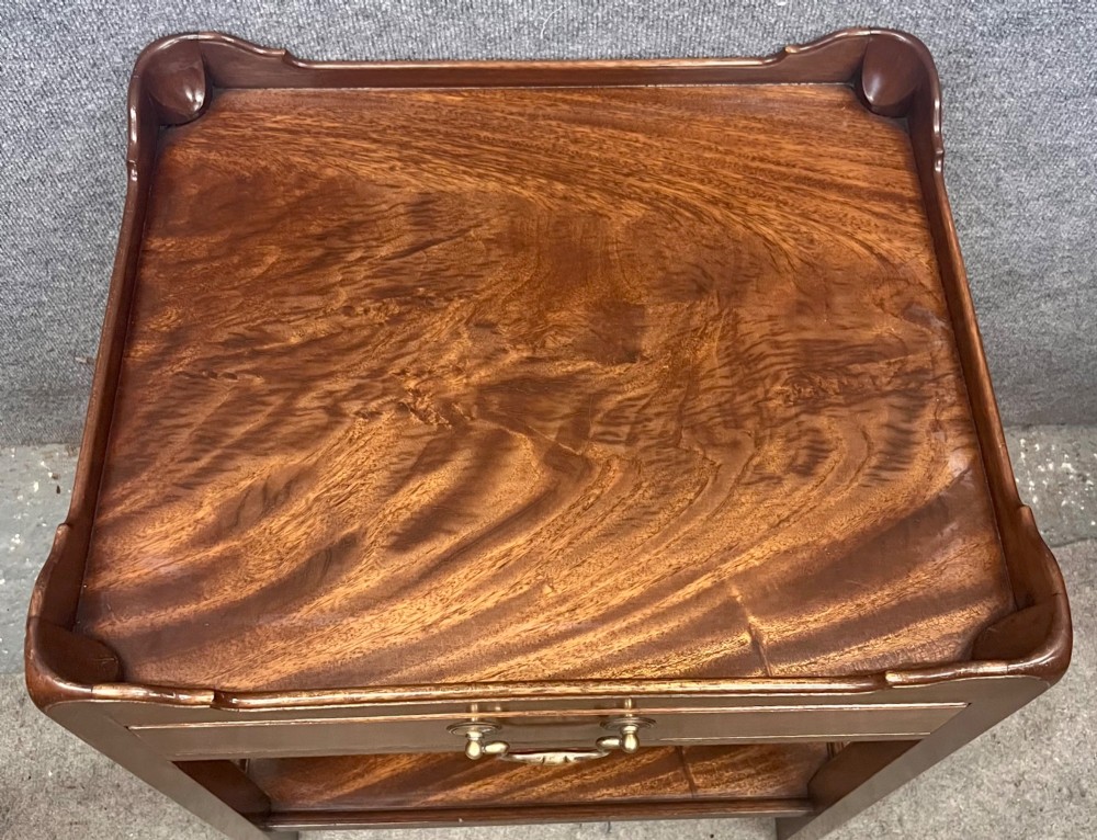 A matching pair of Georgian style mahogany bedside tables featuring flame mahogany tops with shaped gallery edges, single drawers, and open lower shelves. View V