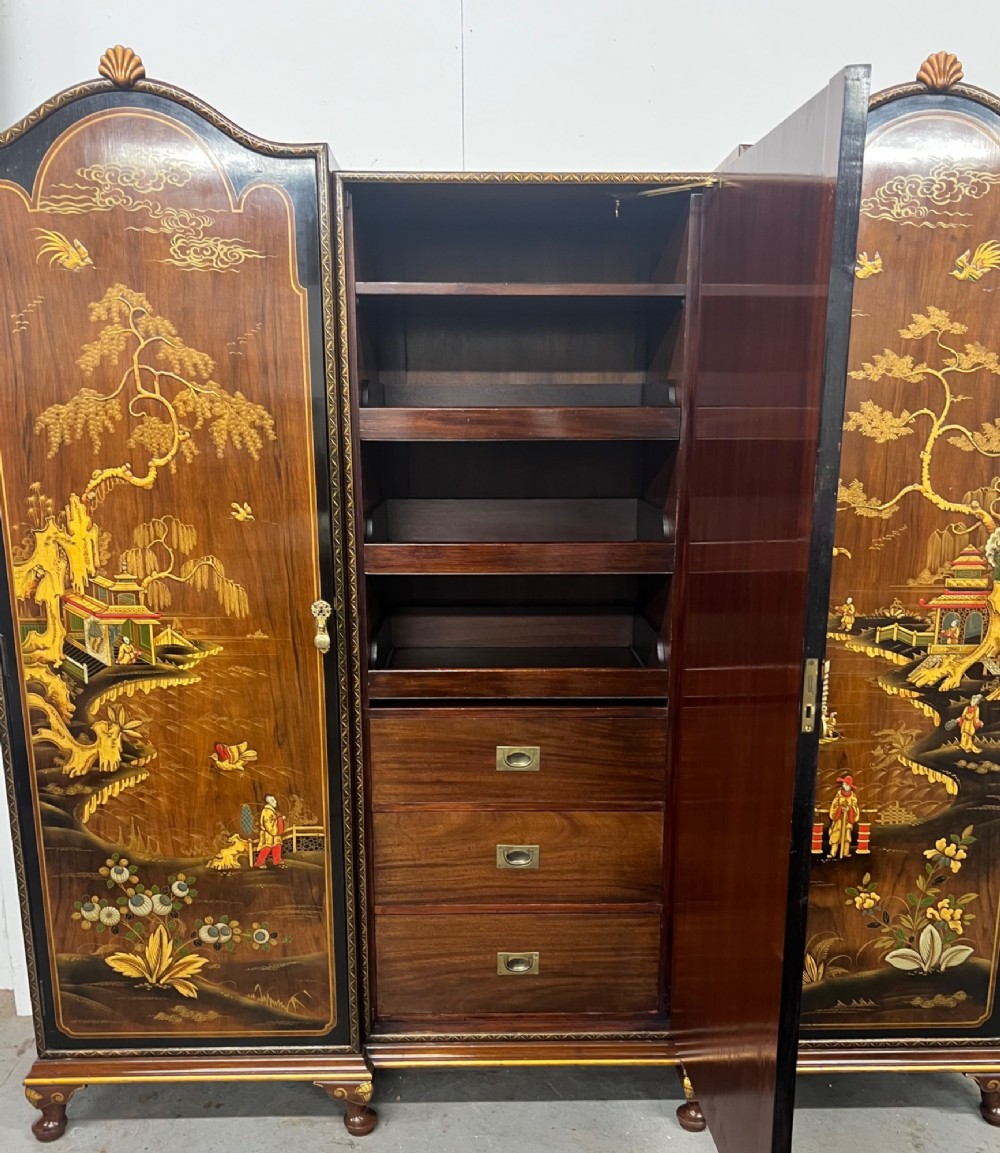 A triple-door Chinoiserie wardrobe featuring intricate gilded Asian landscape scenes, shell-carved crests, and dark polished wood frames. View II