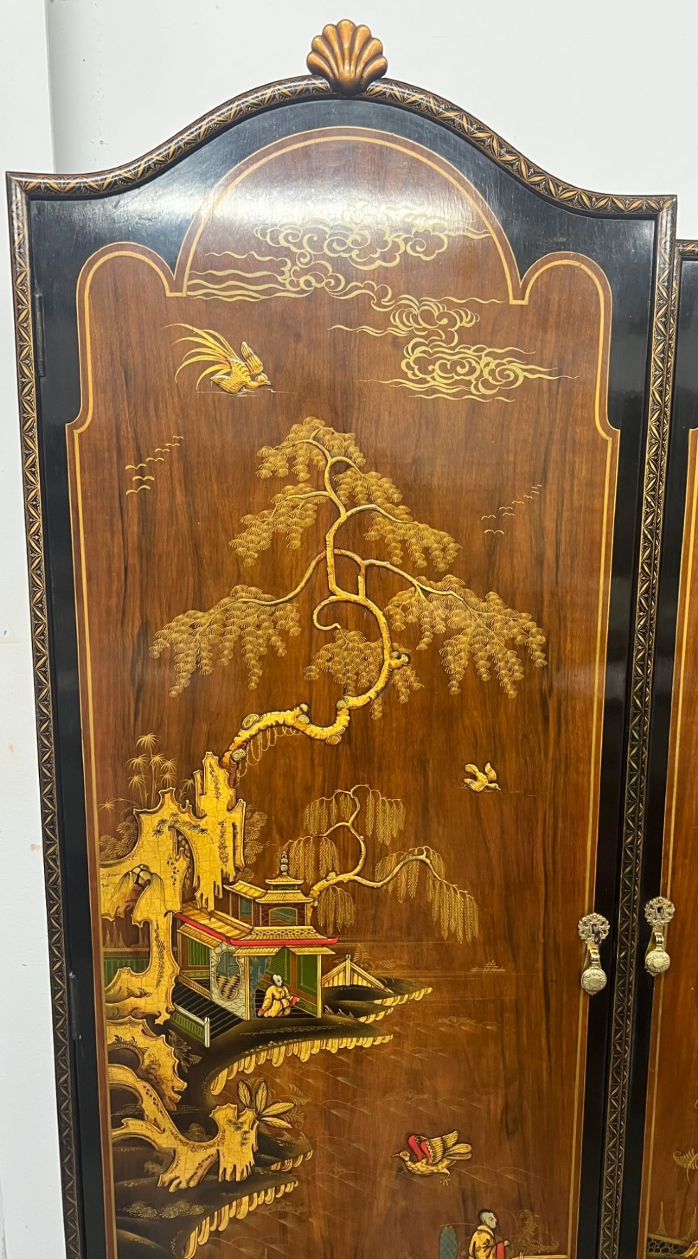 A triple-door Chinoiserie wardrobe featuring intricate gilded Asian landscape scenes, shell-carved crests, and dark polished wood frames. View V