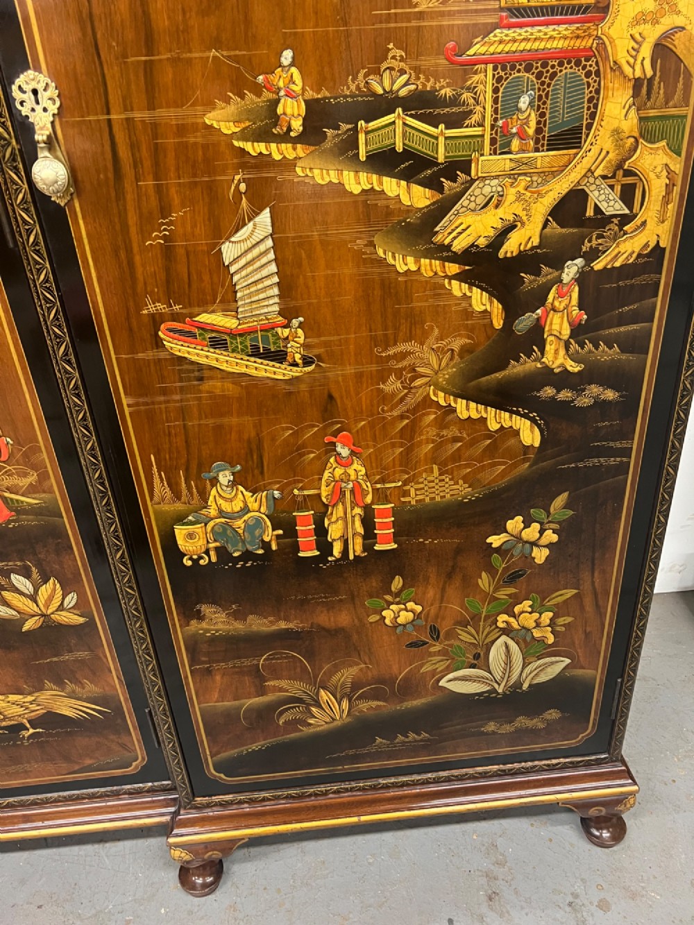 A triple-door Chinoiserie wardrobe featuring intricate gilded Asian landscape scenes, shell-carved crests, and dark polished wood frames. View VIII
