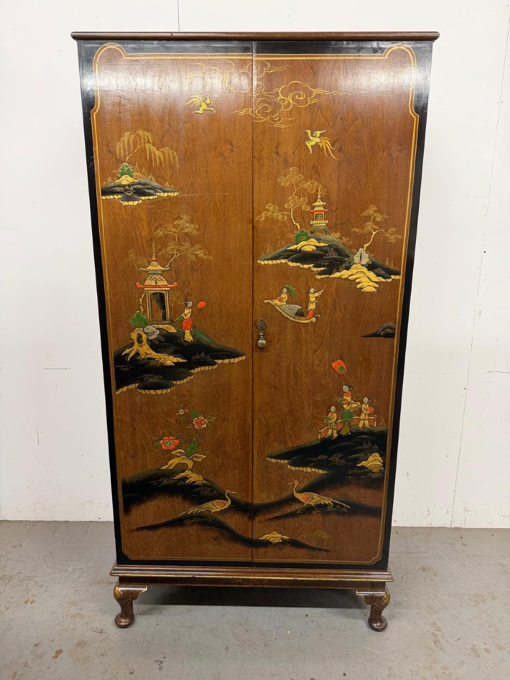 A two-door wooden compactum wardrobe decorated with hand-painted Chinoiserie scenes, pagodas, and figures set within dark lacquered borders. View XII
