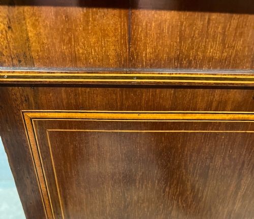 An Edwardian demi-lune mahogany cabinet featuring twin doors with oval inlaid veneer panels and short tapered legs. View V