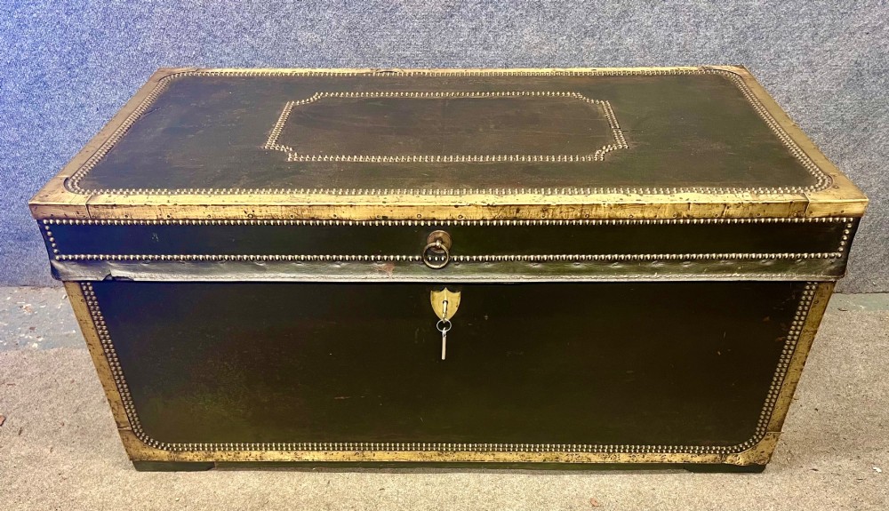 An early nineteenth-century camphor wood campaign trunk wrapped in dark olive green leather with brass stud borders, brass corner plates, side handles, and a key lock. View II