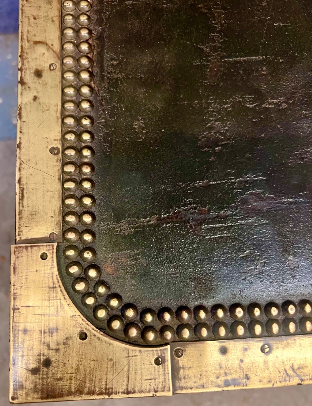 An early nineteenth-century camphor wood campaign trunk wrapped in dark olive green leather with brass stud borders, brass corner plates, side handles, and a key lock. View IV