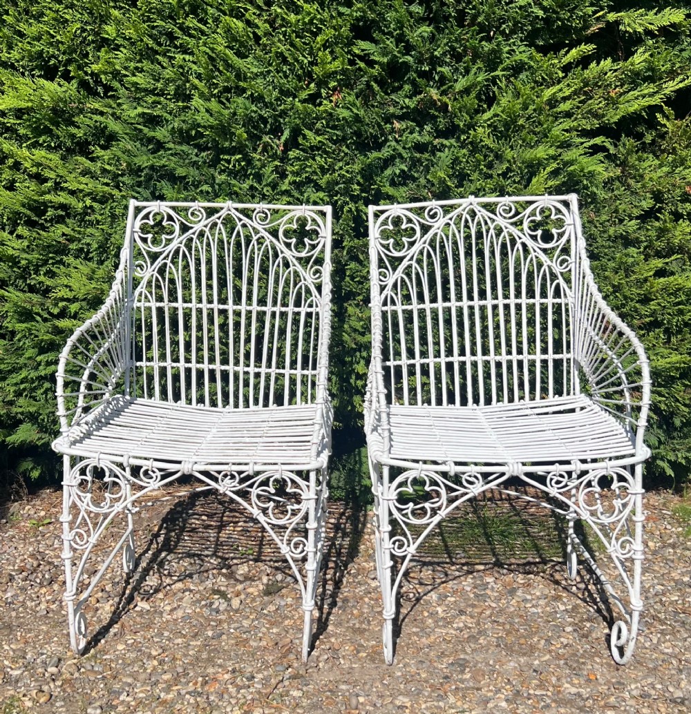 A pair of white painted iron garden chairs featuring Gothic arched backs, slatted wire seats, and scrolled feet. View II