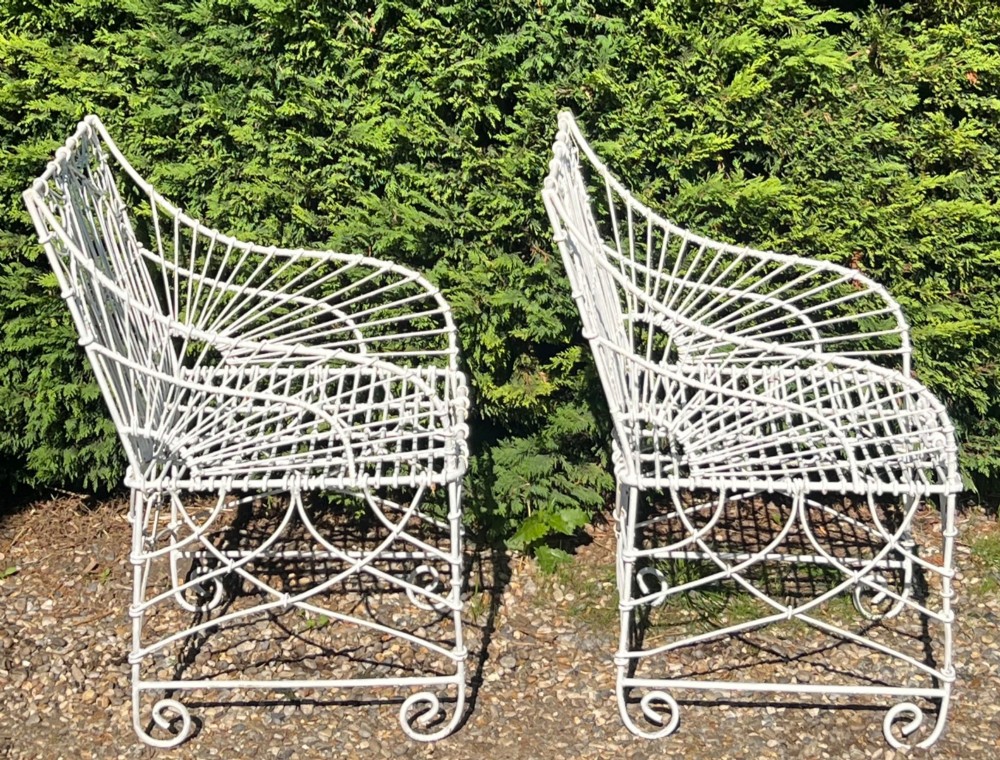A pair of white painted iron garden chairs featuring Gothic arched backs, slatted wire seats, and scrolled feet. View VI