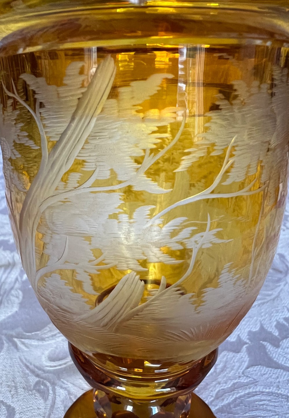 An amber glass lidded pokal vase featuring wheel-engraved woodland imagery with a stag, a faceted stem, and a stepped lid. View VI
