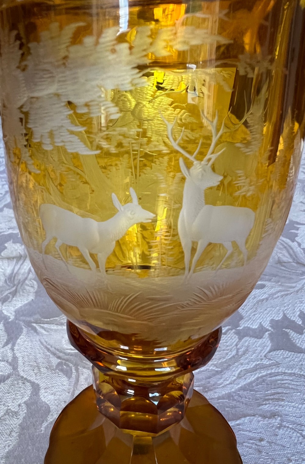 An amber glass lidded pokal vase featuring wheel-engraved woodland imagery with a stag, a faceted stem, and a stepped lid. View VII
