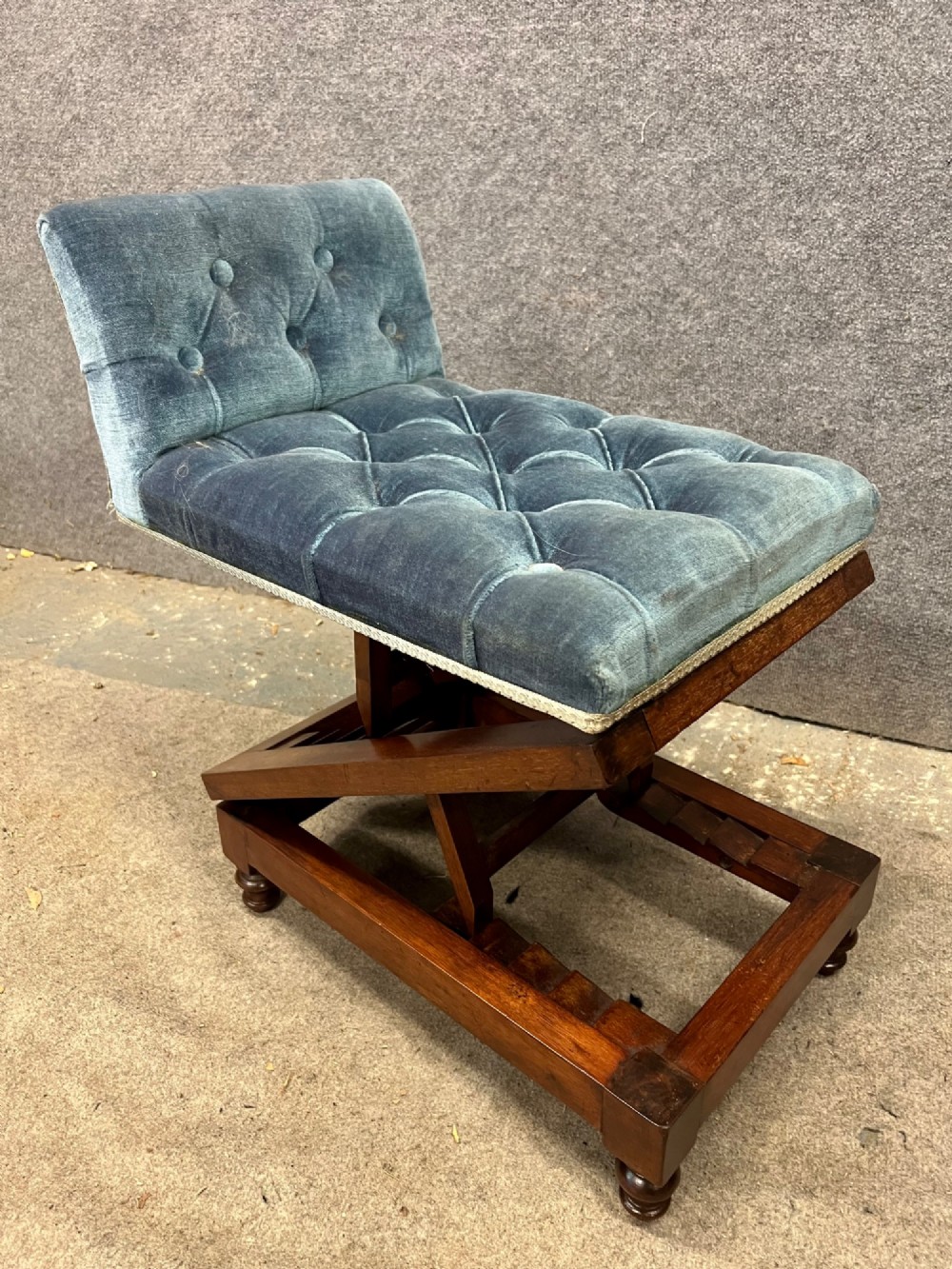 A 19th-century mahogany gout stool featuring an adjustable ratcheted frame and button-tufted blue velvet upholstery on turned feet. View VII