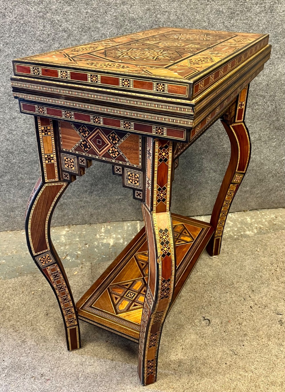 A Syrian games table featuring geometric micro-mosaic wood inlay, curved cabriole legs, and a fitted lower shelf. View III