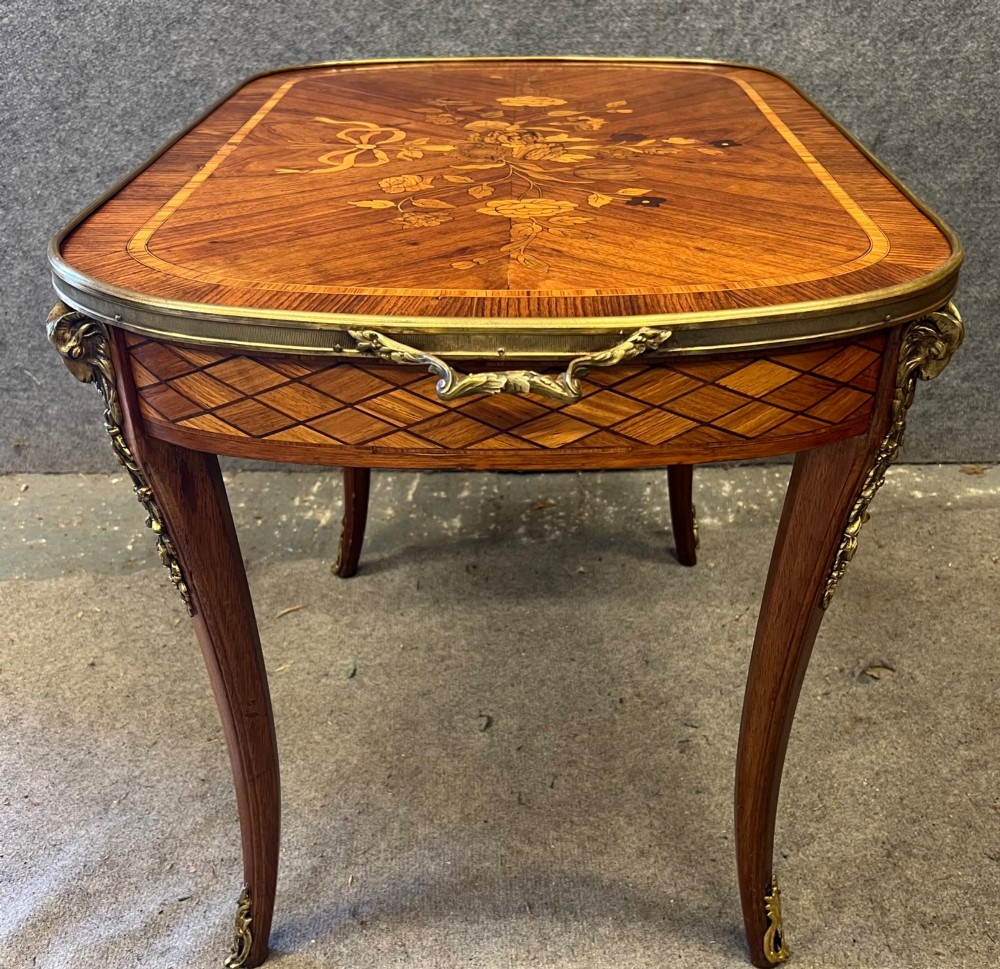 A French style low coffee table featuring floral marquetry inlay on top, diamond parquetry sides, cabriole legs, and brass corner mounts. View VI